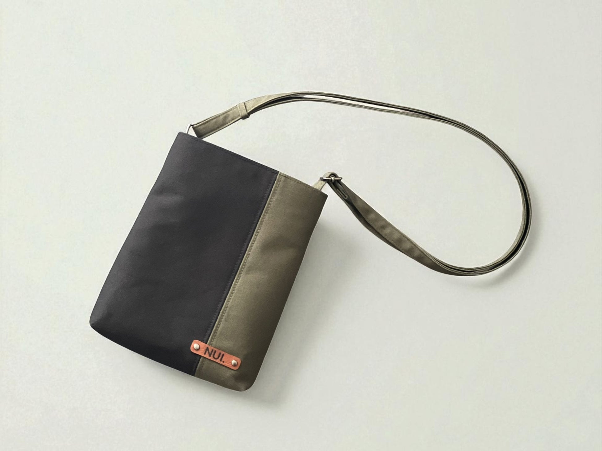 Top view of dark olive and black crossbody bag with adjustable strap.