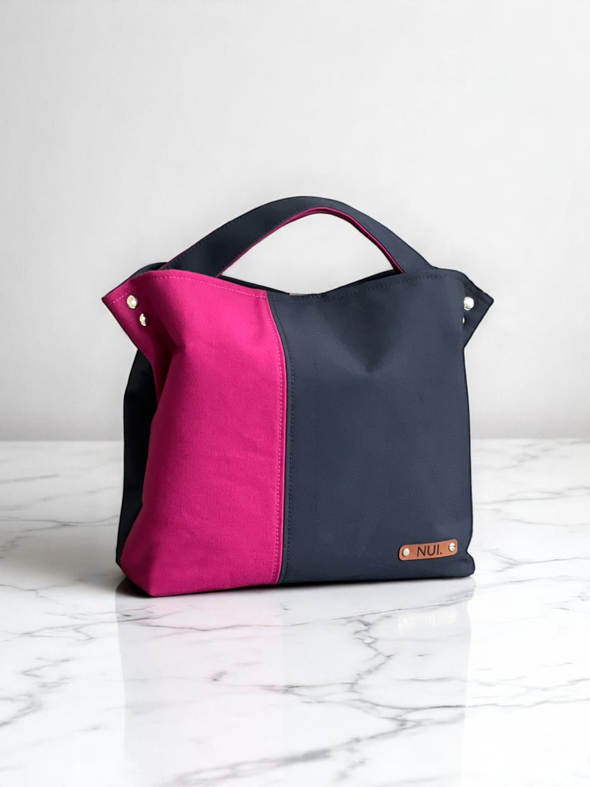 NUIdesign tote bag in Midnight and Fuchsia Rose canvas, showing bold two-tone colour and structured style.