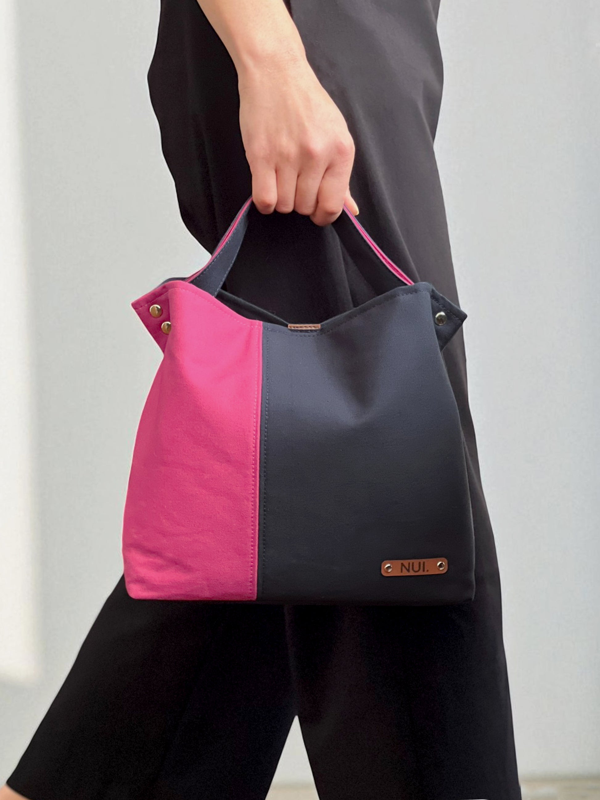 Model holding the NUIdesign Midnight and Fuchsia Rose two-tone tote bag by the handle, handmade in Melbourne from Japanese cotton canvas.