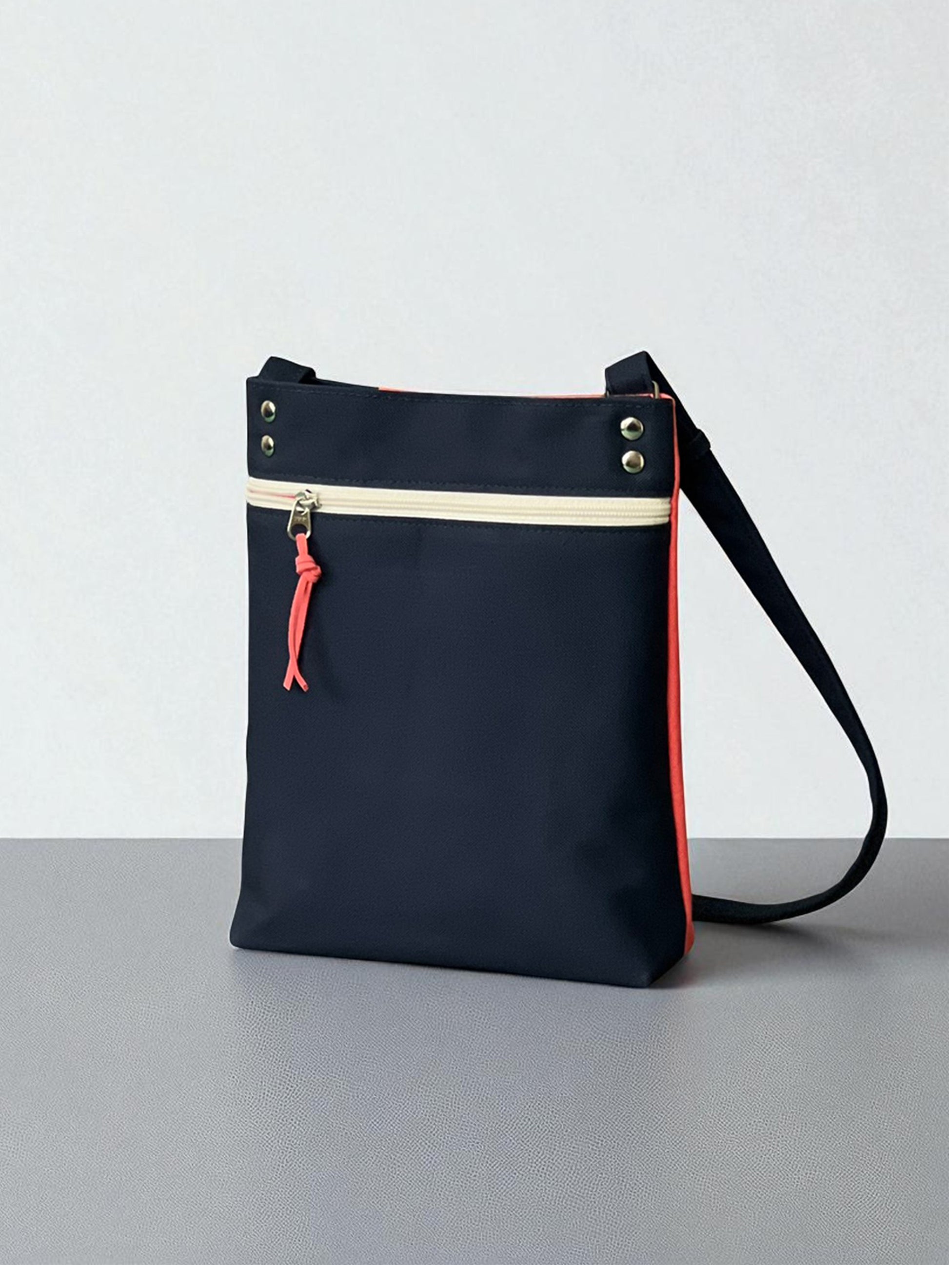 Back of navy and coral cotton canvas crossbody bag with zipper pocket, handmade by NUIdesign.