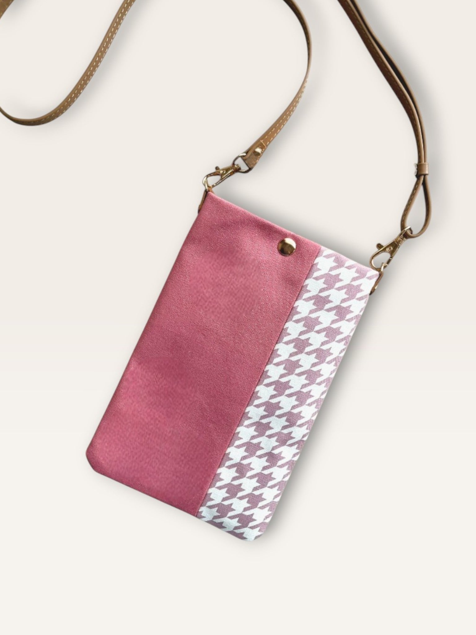 A handmade fabric pouch with a smoky pink panel and a pink-and-white houndstooth pattern on the right. It features a tan-colored adjustable shoulder strap.

