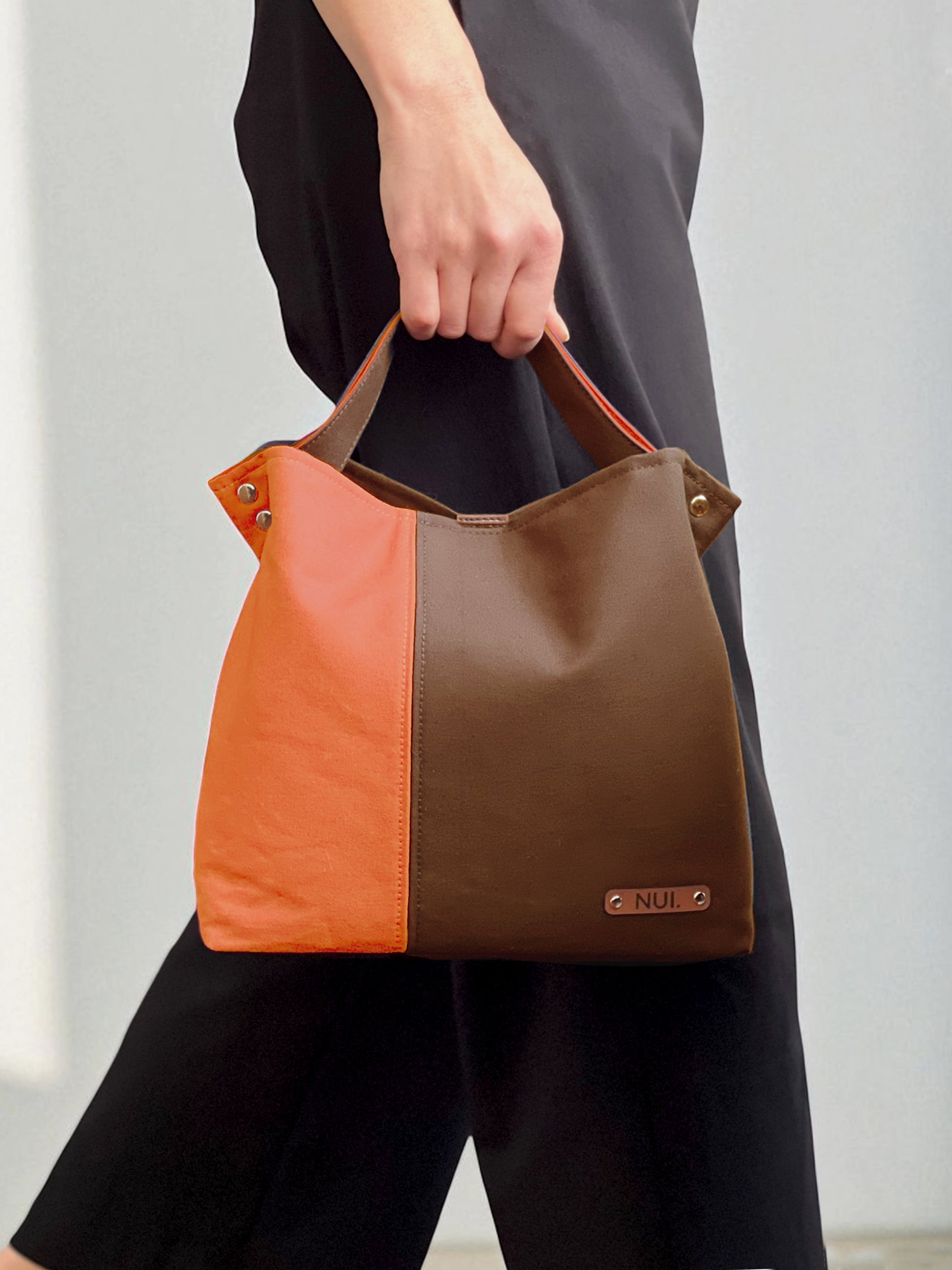 Model holding the NUIdesign Brown and Terracotta two-tone tote bag by the handle, slow-crafted in Melbourne from Japanese cotton canvas.